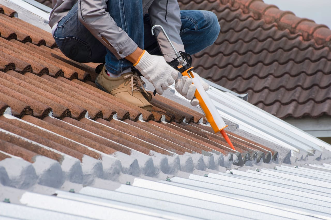 Roofer repairing tiles on a pitched roof in Berkshire